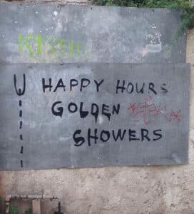 Das Bild zeigt eine Mauer mit Graffiti-Schriftzug: »Happy Hours Golden Showers« und dient als Beitragsbild für das Thema „Häufige sexuelle Fetische“.