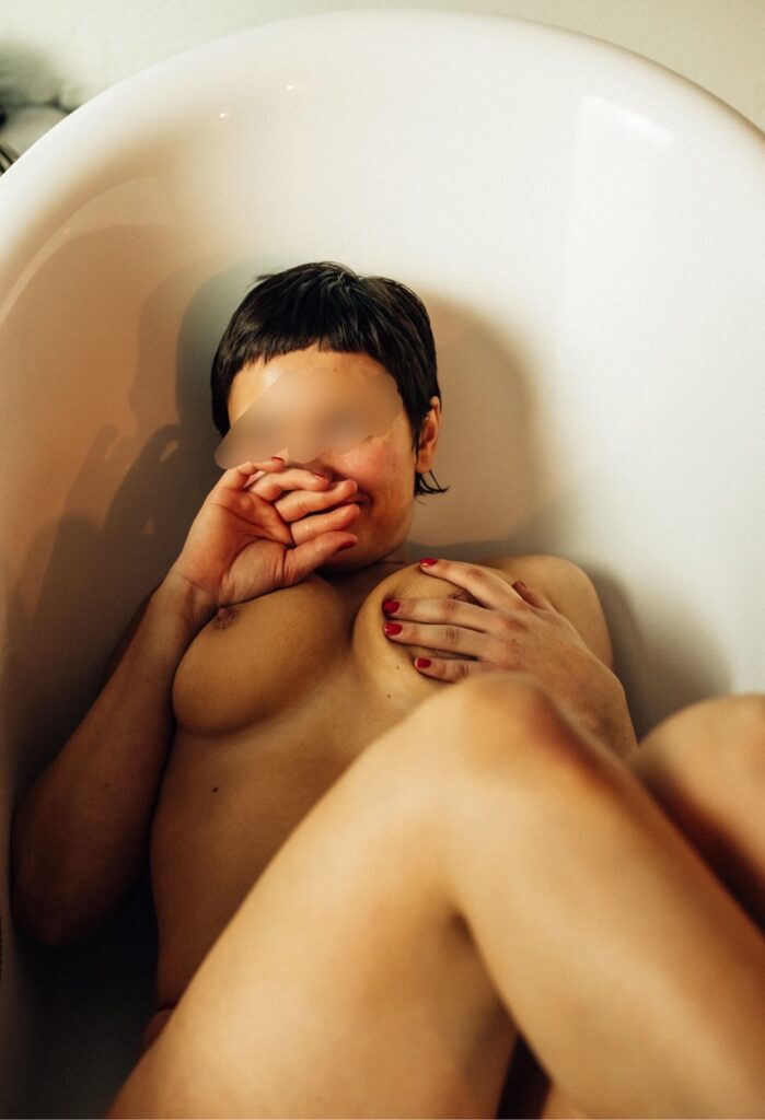 Hier sieht man eine Frau, sie liegt nackt in einer Badewanne.